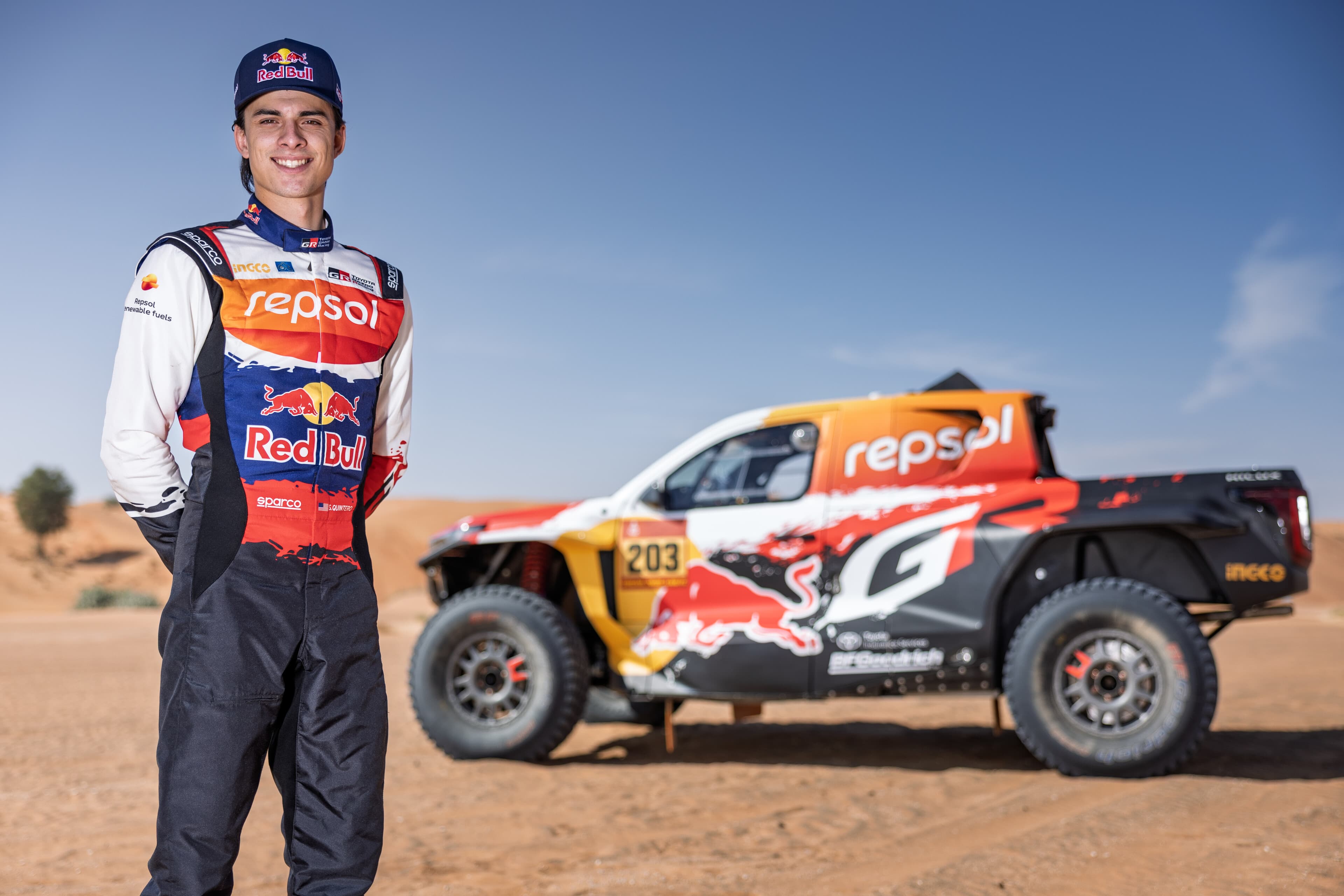 Seth Quintero in his Red Bull Toyota Gazoo Racing suit beside the Hilux T1+
