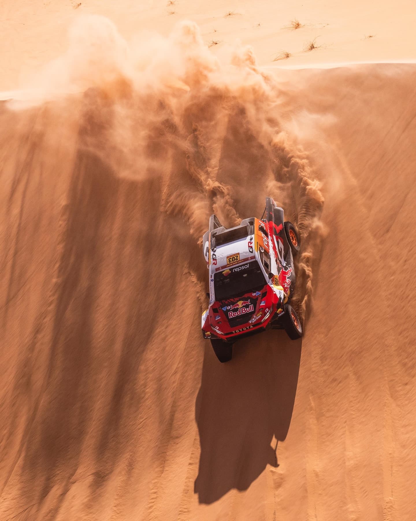 Seth Quintero's rally car charging up a dune in a wall of sand