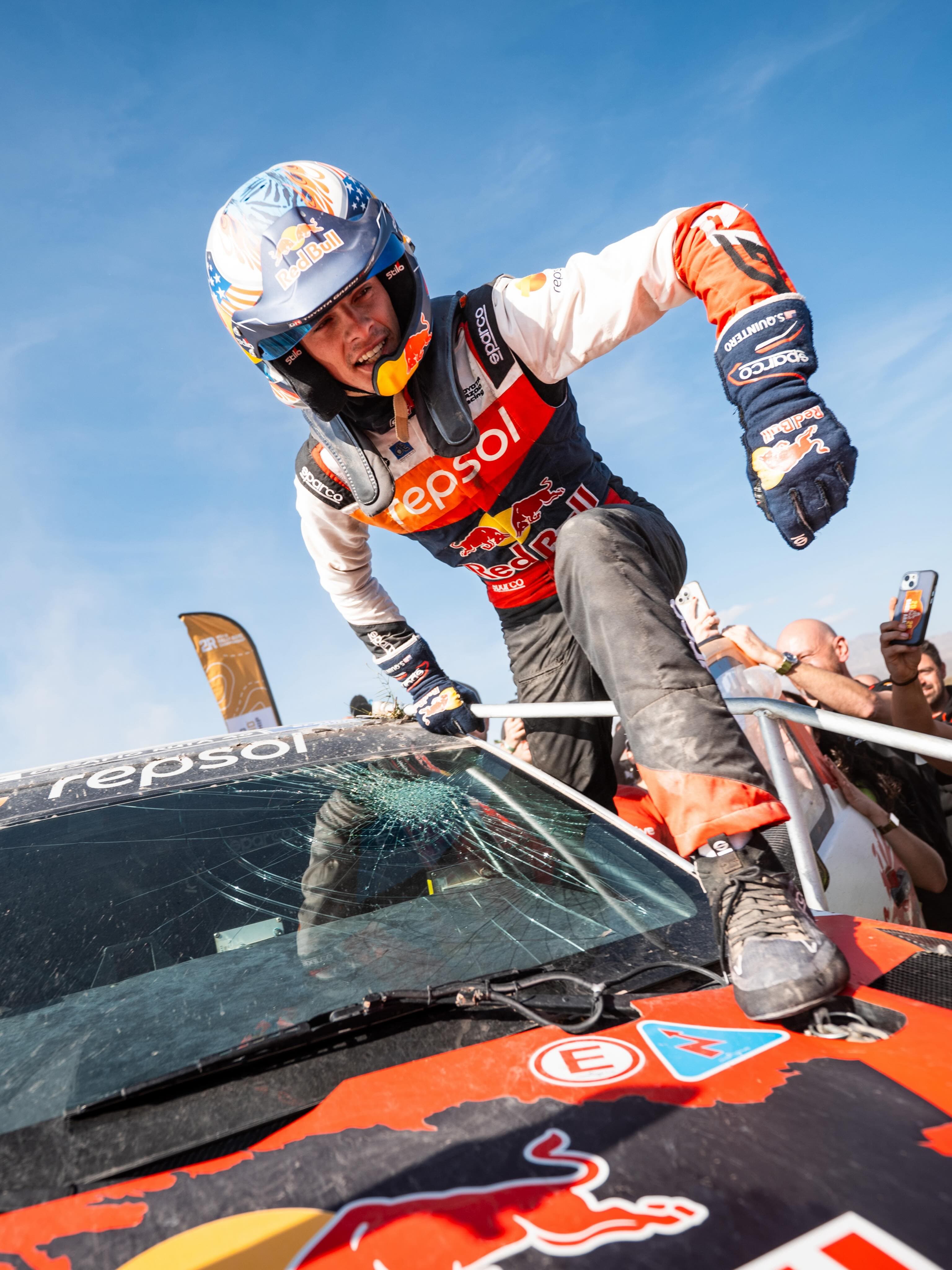 Seth Quintero climbing out of his car through a cracked windscreen after a stage